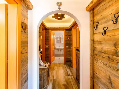 a hallway with an archway and a room with wooden walls at Apartment Brunel-2 by Interhome in Pozza di Fassa