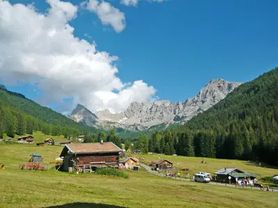 a group of buildings in a field with mountains in the background at Apartment Brunel-2 by Interhome in Pozza di Fassa