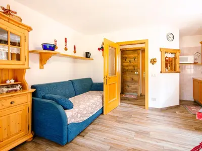 a kitchen with wooden cabinets and a table with chairs at Apartment Brunel-2 by Interhome in Pozza di Fassa