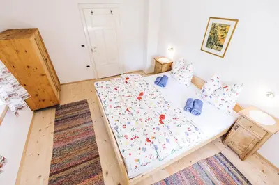 a bedroom with a large bed with white sheets and blue pillows at Untersteinhaus in Aldino