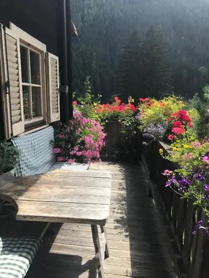 a wooden bench sitting outside of a house with flowers at Bauernhaus Spathen in Santa Valburga St. Walburg