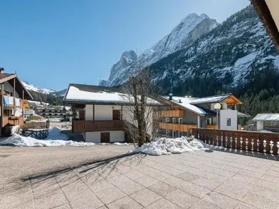 a building with snow covered mountains in the background at Apartment Cesa Micheluzzi - CZI712 by Interhome in Penia