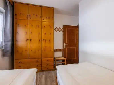 a bedroom with two beds and a wooden cabinet at Apartment Cesa Micheluzzi - CZI712 by Interhome in Penia