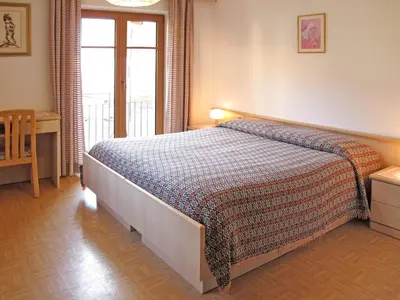 a bedroom with a bed and a desk and a window at Apartment Lola by Interhome in Moena