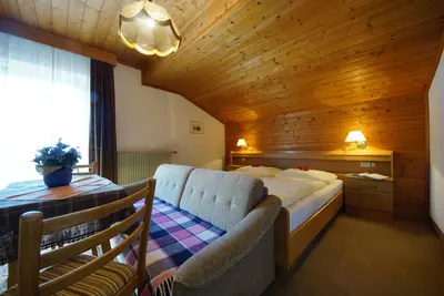 a bedroom with a bed and a chair in a room at Garni Flurida in Badia