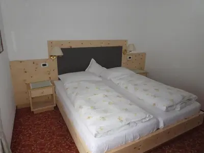 a bedroom with a large bed with a wooden headboard at Garni Flurida in Badia
