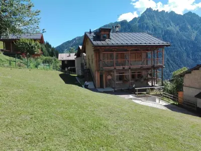 a large building on a hill with mountains in the background at Tabià Fregona, Chalet Alpino con vista e stile tradizionale in Fregona