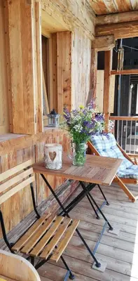 a wooden table with a vase of flowers on a porch at Tabià Fregona, Chalet Alpino con vista e stile tradizionale in Fregona