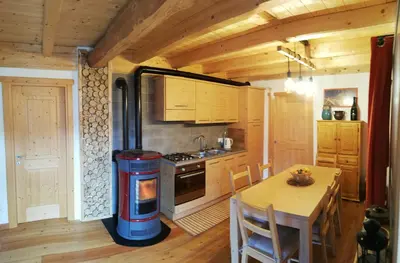 a kitchen with a stove and a table in a room at Tabià Fregona, Chalet Alpino con vista e stile tradizionale in Fregona