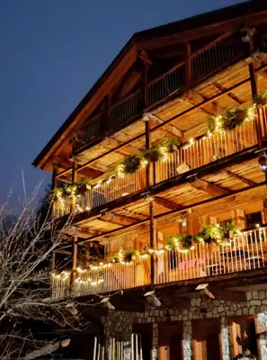 a building with a balcony with lights on it at Tabià Fregona, Chalet Alpino con vista e stile tradizionale in Fregona