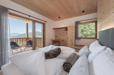 a bedroom with a white bed and a large window at Gschlunerhof in Castelrotto