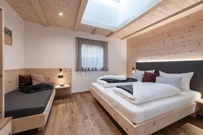 two beds in a room with wooden floors and a window at Gschlunerhof in Castelrotto