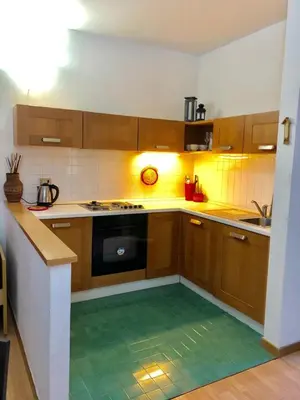 a kitchen with wooden cabinets and a green tile floor at Appartamento AB in Passo San Pellegrino