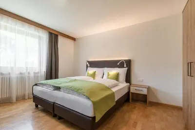 a bedroom with a bed and a large window at Ciasa MAEL Dolomites Apartments in La Valle