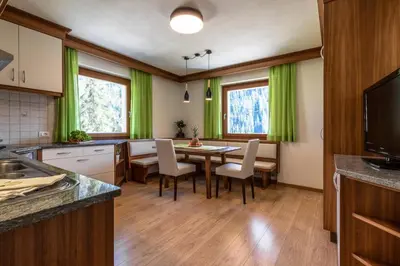 a kitchen with green curtains and a table and chairs at Ciasa MAEL Dolomites Apartments in La Valle
