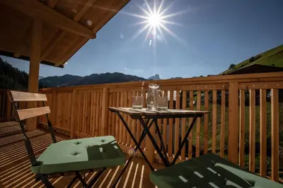 a table and two chairs on a wooden deck at Ciasa MAEL Dolomites Apartments in La Valle