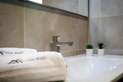 a bathroom with a sink and a tub with towels at Ciasa MAEL Dolomites Apartments in La Valle