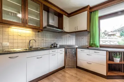 a kitchen with white cabinets and a window at Ciasa MAEL Dolomites Apartments in La Valle
