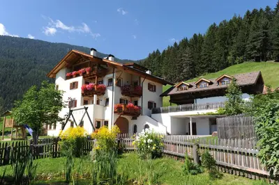 a white house with flowers on the side of it at Prackfiedererhof in Villandro