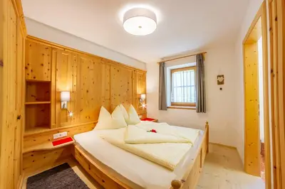 a bedroom with a bed with wooden walls and a window at Prackfiedererhof in Villandro