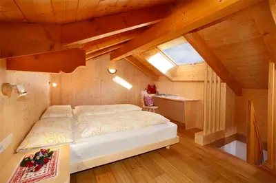 a bedroom with a bed in a wooden attic at Grohmann Apartments in Selva di Val Gardena