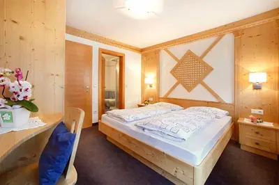 a bedroom with a wooden bed and a desk and a bed sidx sidx at Grohmann Apartments in Selva di Val Gardena