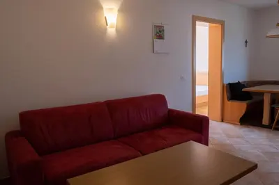 a living room with a red couch and a table at Fewo Dreiraum im Haus Götsch 6 in Parcines
