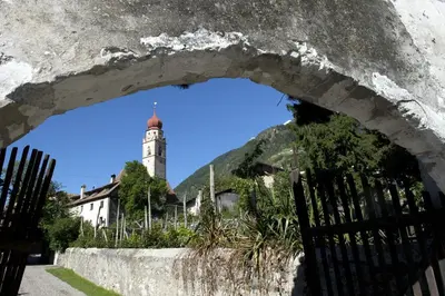 an arch in a wall with a clock tower in the background at Fewo Dreiraum im Haus Götsch 6 in Parcines