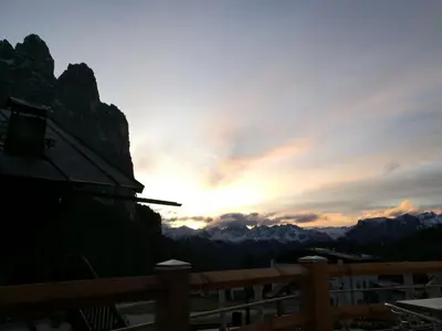 a sunset over the mountains with a wooden fence at Rifugio Stella Alpina Spiz Piaz per escursionisti in Gardeccia - San Giovanni di Fassa