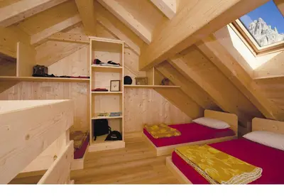 a room with two beds in a wooden attic at Rifugio Stella Alpina Spiz Piaz per escursionisti in Gardeccia - San Giovanni di Fassa