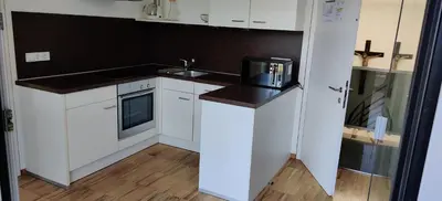a white kitchen with a sink and a microwave at Garni Maria in Varna