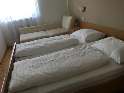 two beds with white sheets and a couch in a room at Garni Maria in Varna