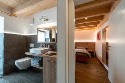 a bathroom with a sink and a toilet and a bedroom at Ciasa Sas da le Doudesc in Vigo di Fassa