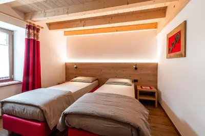 two beds in a room with a red curtain at Ciasa Sas da le Doudesc in Vigo di Fassa
