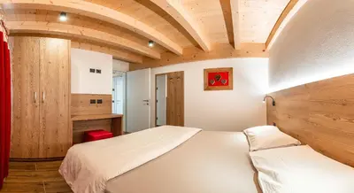 a bedroom with a white bed and a wooden ceiling at Ciasa Sas da le Doudesc in Vigo di Fassa
