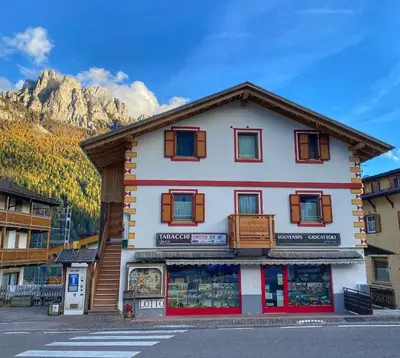 a building with a store in front of a mountain at Ciasa Sas da le Doudesc in Vigo di Fassa