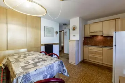 a kitchen with a table with chairs and a refrigerator at Sass Pordoi in Mazzin