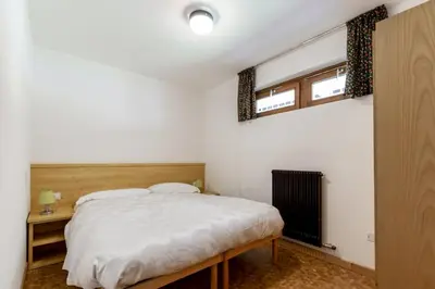 a bedroom with a bed and two windows at Sass Pordoi in Mazzin
