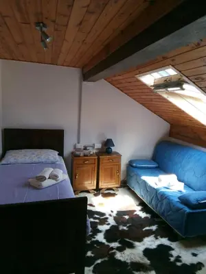 a bedroom with a blue bed and a couch at B&B PRA' DEI CERVI in Telve