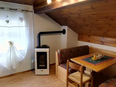 a living room with a wood stove and a table at B&B PRA' DEI CERVI in Telve