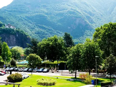 a parking lot with cars parked in front of a mountain at Roma Ariston 8 in Bolzano