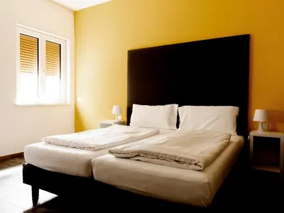 a bedroom with a large white bed with yellow walls at Roma Ariston 8 in Bolzano