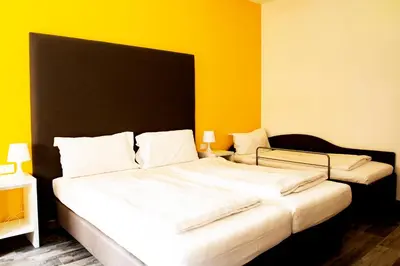 a bedroom with two beds with yellow walls at Roma Ariston 8 in Bolzano