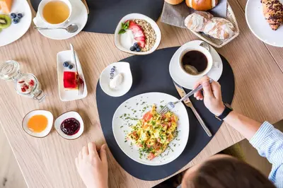 a person eating food on a table with a plate of food at Vinea - Suites in Tirolo