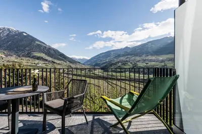 a balcony with a table and chairs and mountains at Vinea - Suites in Tirolo