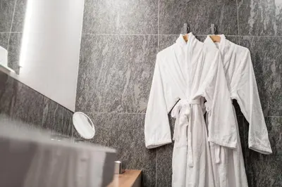 a robe hanging in a bathroom next to a mirror at Vinea - Suites in Tirolo
