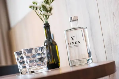 a bottle of wine and a vase of flowers on a table at Vinea - Suites in Tirolo