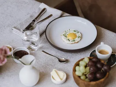 a table with a plate of eggs and a bowl of fruit at Lindenhof Pure Luxury & Spa DolceVita Resort in Naturno