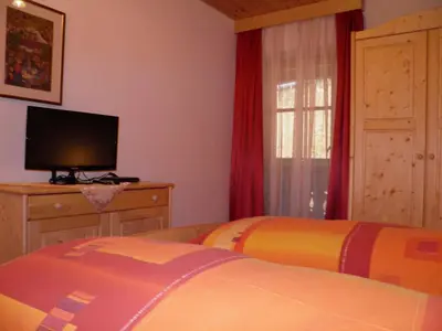 a bedroom with two beds and a flat screen tv at Flatscherhof in San Lorenzo di Sebato