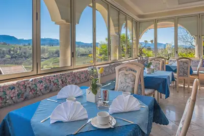 a restaurant with blue tables and chairs and windows at Hotel Weinberg in Appiano sulla Strada del Vino